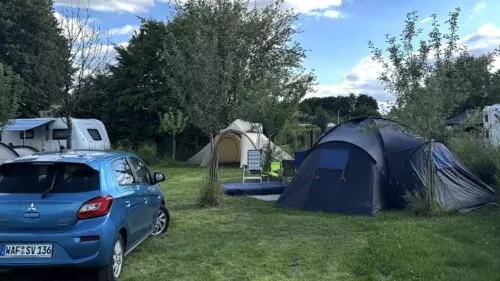 Autos, Caravans und Zelte auf einer Grünfläche